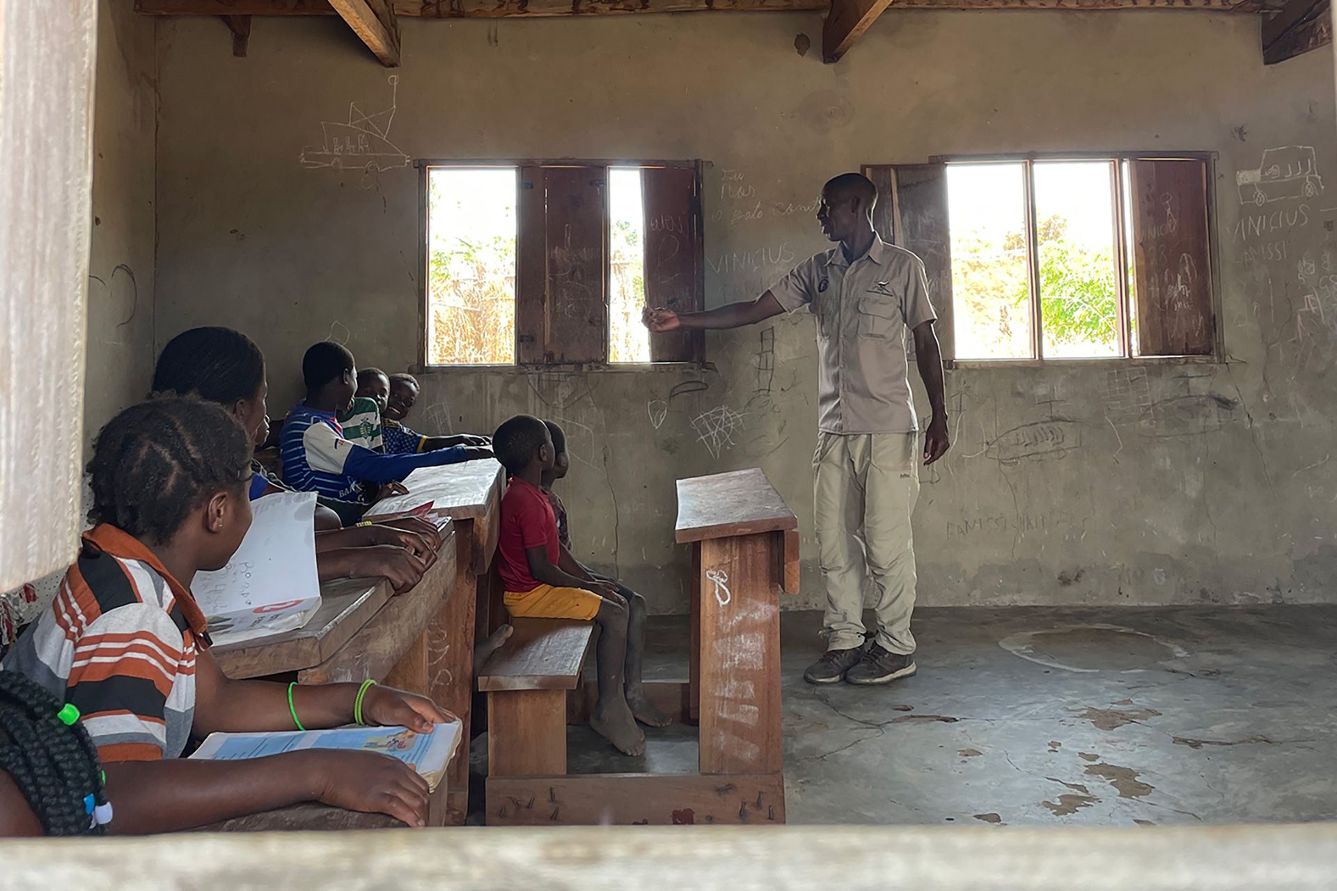 Maique Issufu, community engagement officer at a new REDD+ project, explains the basics of climate change to children in the local primary school. With the project funds, the community hopes to upgrade the school building and equipment.