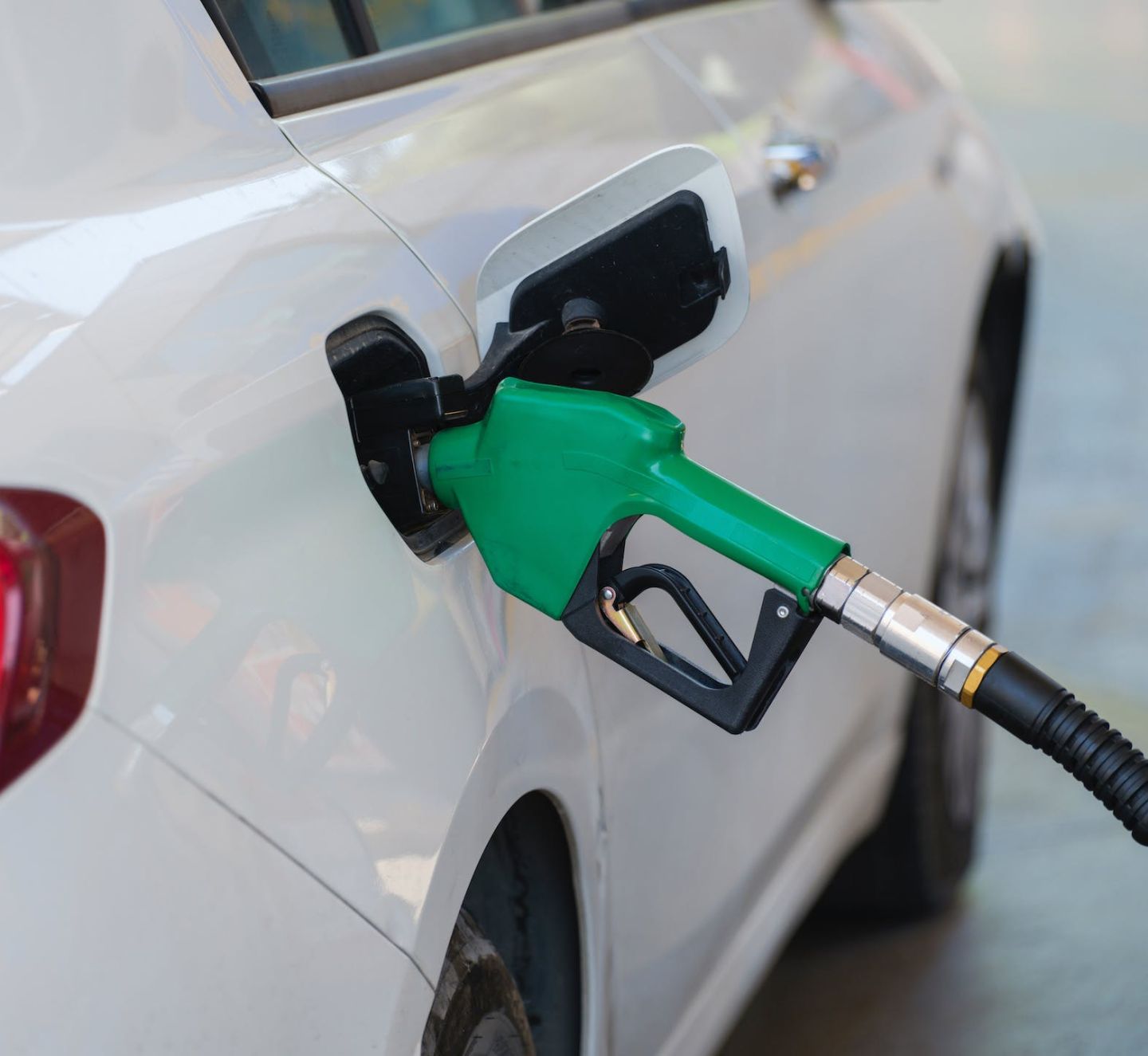 A fuel green pump filling a white car. 
